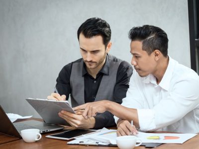 smiling-businessmen-discussing-paperwork-while-sitting-desk